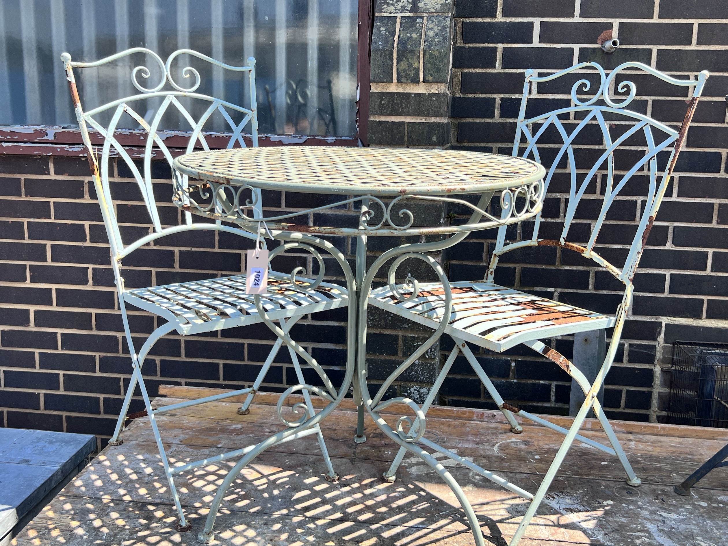 A circular painted metal garden table, diameter 70cm, height 74cm, and two chairs